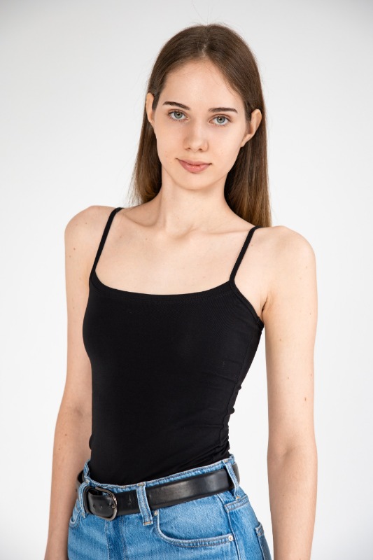 Девушка в черном топе и джинсах на светлом фоне
