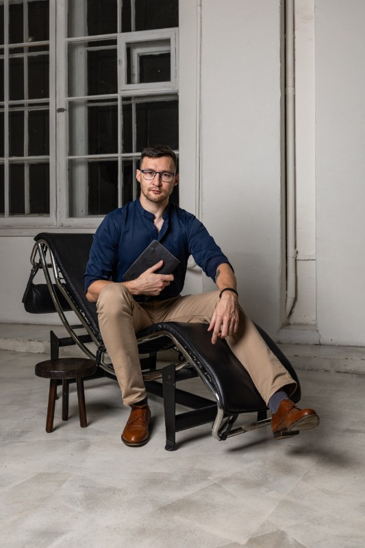 Мужчина в очках и синей рубашке с книгой на шезлонге