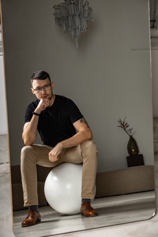 Мужчина в чёрной футболке и бежевых брюках в современном интерьере